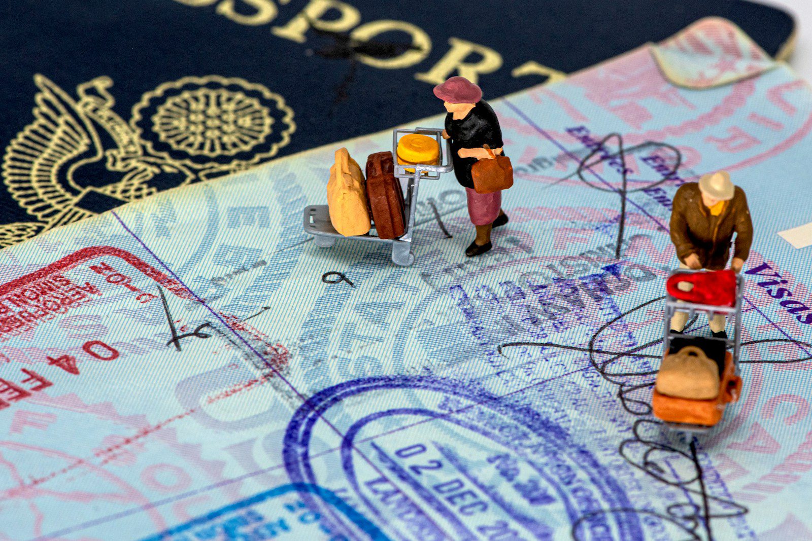 Thailand's ฿3 Million Property Visa Is Suspended. Here's Why I Wouldn't Panic. 5 Passport page with entry stamps and two miniature travellers with luggage